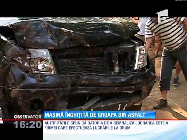 Maşină &icirc;nghiţită de groapa din asfalt