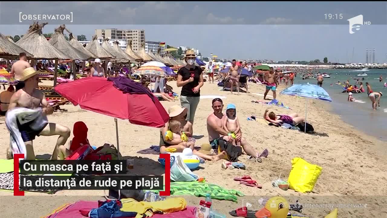 Cu masca pe față și la distanță de rude pe plajă